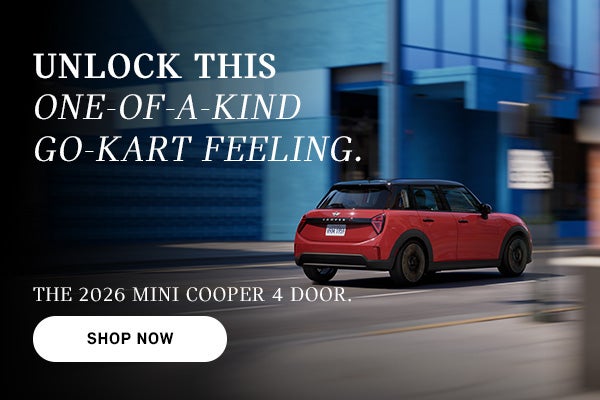 Red MINI Cooper 4-door driving on a city street, with motion blur in the background and ad text promoting the 2026 model