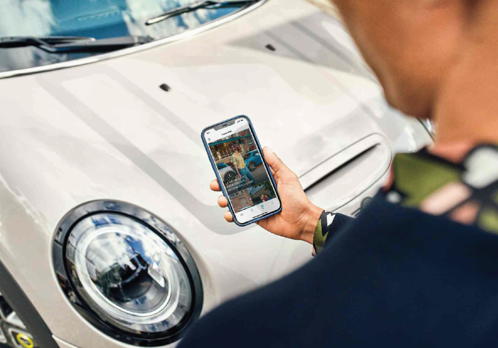 Man looking at phone next to a MINI